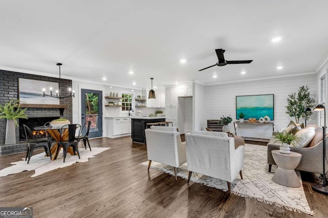 living area featuring crown molding, a ceiling fan, a fireplace, dark wood finished floors, and recessed lighting