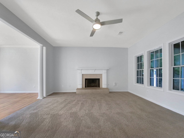 unfurnished living room with carpet floors, ceiling fan, and ornate columns