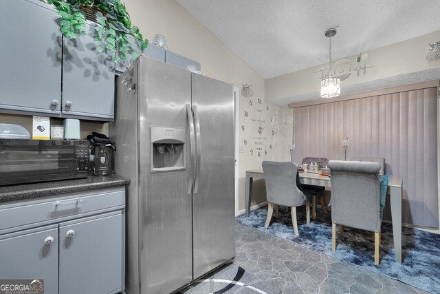 kitchen featuring lofted ceiling, hanging light fixtures, gray cabinetry, carpet, and stainless steel refrigerator with ice dispenser