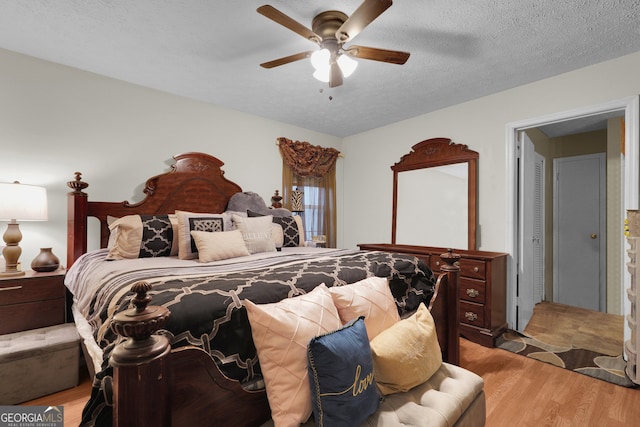 bedroom with a textured ceiling, light hardwood / wood-style floors, and ceiling fan