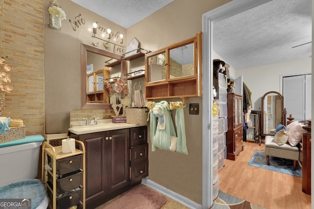 bathroom with a textured ceiling, toilet, vanity, and hardwood / wood-style floors