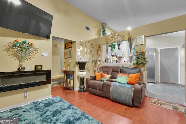 living room featuring wood-type flooring and vaulted ceiling