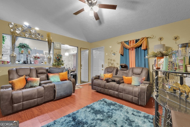 living room with ceiling fan, vaulted ceiling, a textured ceiling, and hardwood / wood-style floors