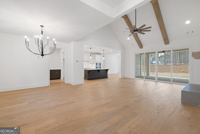 unfurnished living room with ceiling fan with notable chandelier, beam ceiling, high vaulted ceiling, and light hardwood / wood-style flooring