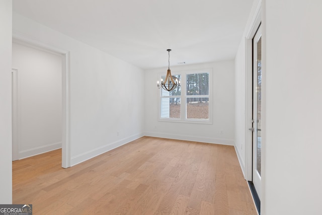 unfurnished room featuring a chandelier and light hardwood / wood-style floors