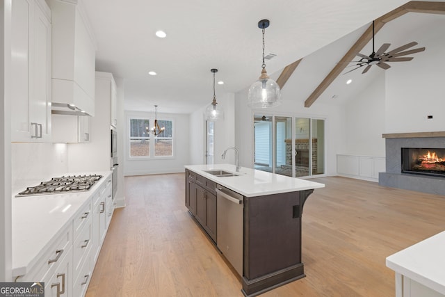 kitchen featuring appliances with stainless steel finishes, pendant lighting, sink, white cabinets, and a center island with sink