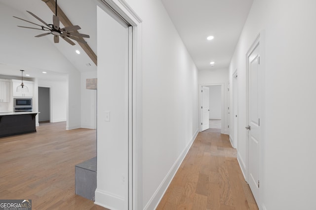 corridor with lofted ceiling with beams and light hardwood / wood-style floors