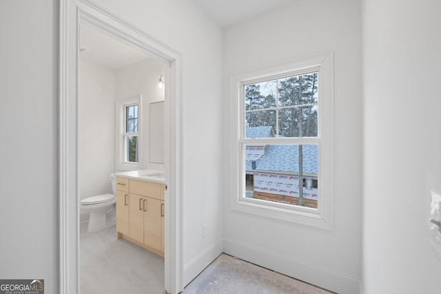 bathroom featuring concrete flooring, vanity, plenty of natural light, and toilet