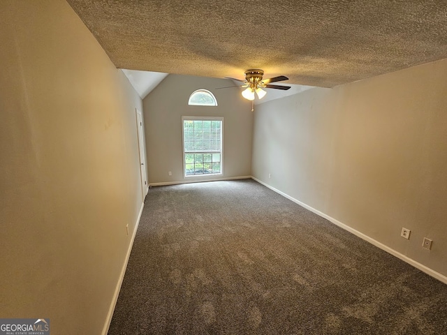 carpeted empty room featuring lofted ceiling, ceiling fan, and a textured ceiling