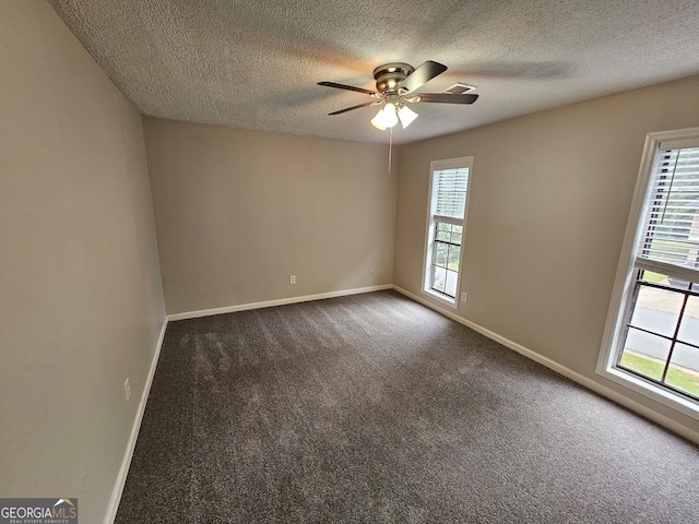 spare room featuring a textured ceiling, dark colored carpet, and ceiling fan