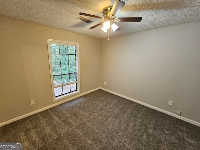 spare room with ceiling fan, a textured ceiling, and dark carpet