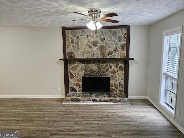 room details featuring ceiling fan, a stone fireplace, a textured ceiling, and hardwood / wood-style floors