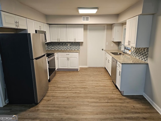 kitchen featuring decorative backsplash, light wood-type flooring, white cabinetry, and appliances with stainless steel finishes