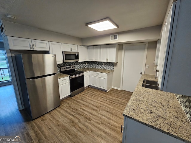 kitchen with light stone countertops, dark wood-type flooring, stainless steel appliances, and white cabinets