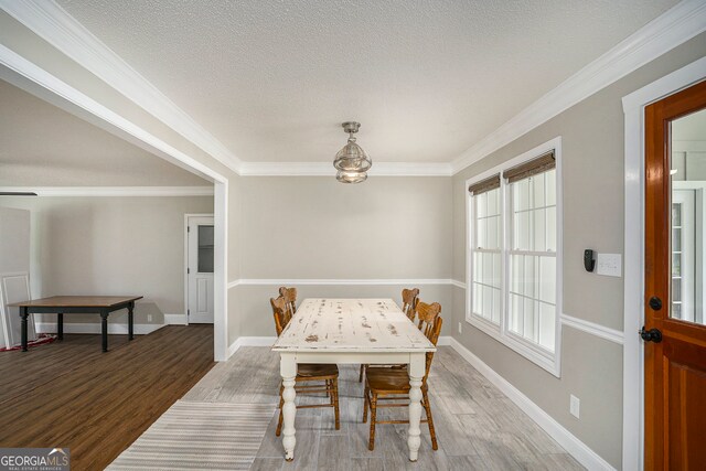 dining room with ornamental molding, a textured ceiling, and hardwood / wood-style flooring