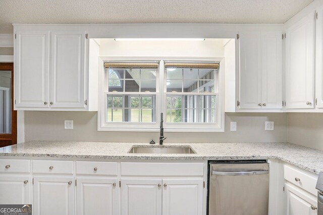 kitchen with stainless steel dishwasher, sink, white cabinetry, and light stone countertops