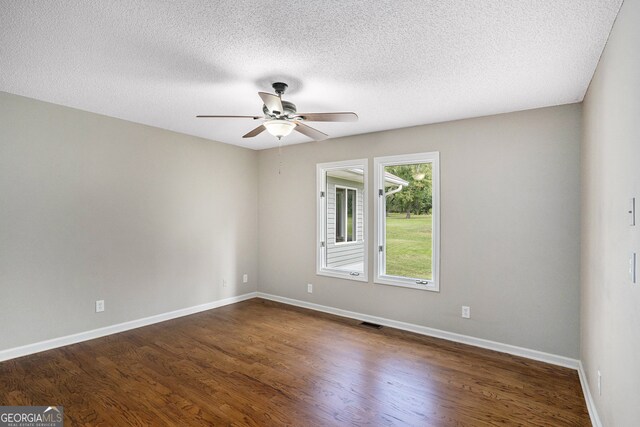 empty room featuring a textured ceiling, dark hardwood / wood-style floors, and ceiling fan