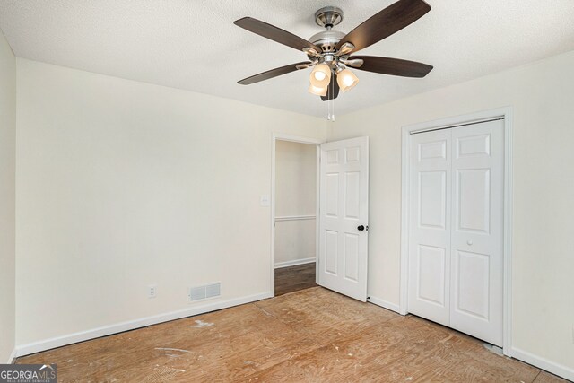 unfurnished bedroom with light hardwood / wood-style flooring, a textured ceiling, a closet, and ceiling fan