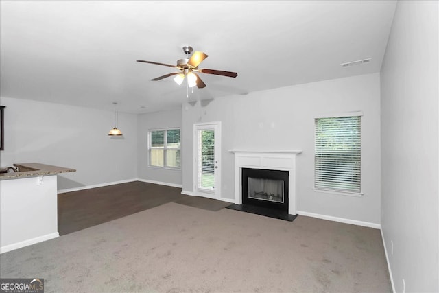 unfurnished living room with dark colored carpet and ceiling fan