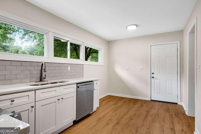 kitchen with white cabinets, sink, stainless steel dishwasher, light wood-type flooring, and tasteful backsplash