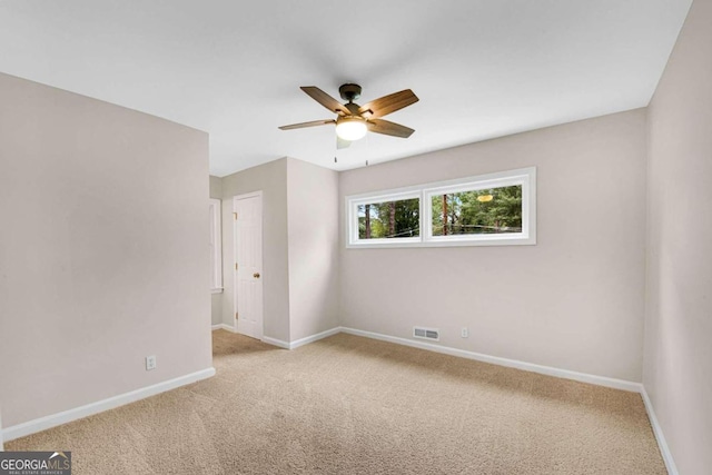 empty room featuring ceiling fan and light colored carpet