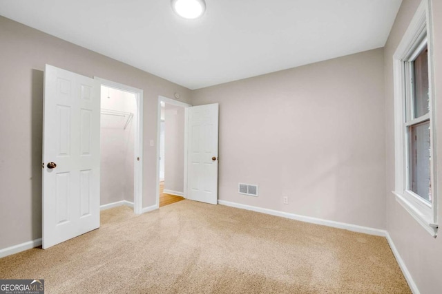 unfurnished bedroom featuring light colored carpet and a closet