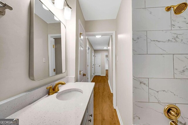 bathroom with vanity, wood-type flooring, and tiled shower