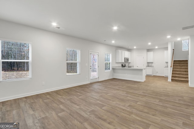 unfurnished living room with light wood-type flooring and plenty of natural light