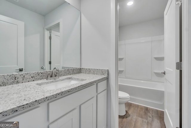 full bathroom featuring  shower combination, vanity, toilet, and hardwood / wood-style flooring