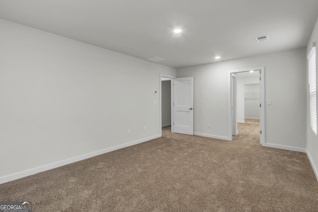 unfurnished bedroom featuring a spacious closet, light colored carpet, and a closet