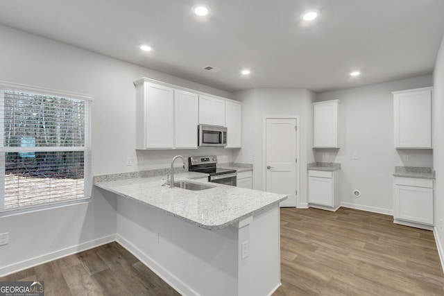 kitchen featuring white cabinets, stainless steel appliances, kitchen peninsula, and light hardwood / wood-style flooring