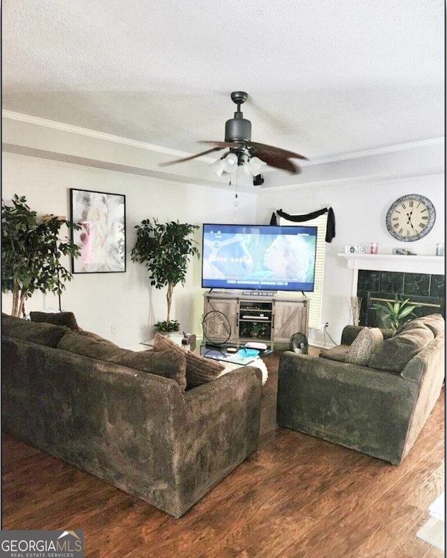 living room with wood-type flooring, ceiling fan, a fireplace, and a textured ceiling