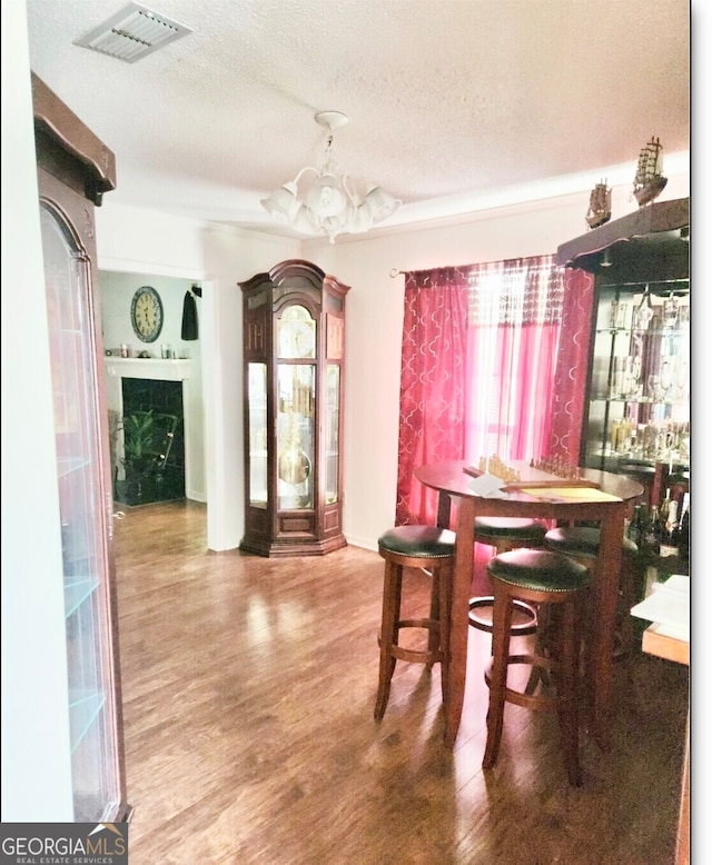 dining space featuring an inviting chandelier, a textured ceiling, and hardwood / wood-style floors