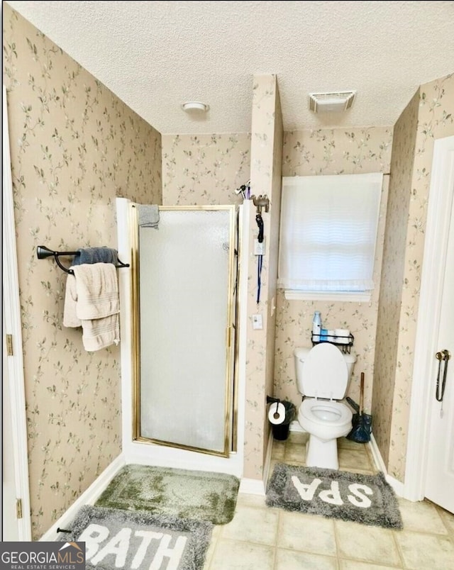 bathroom with a textured ceiling, tile patterned flooring, toilet, and an enclosed shower