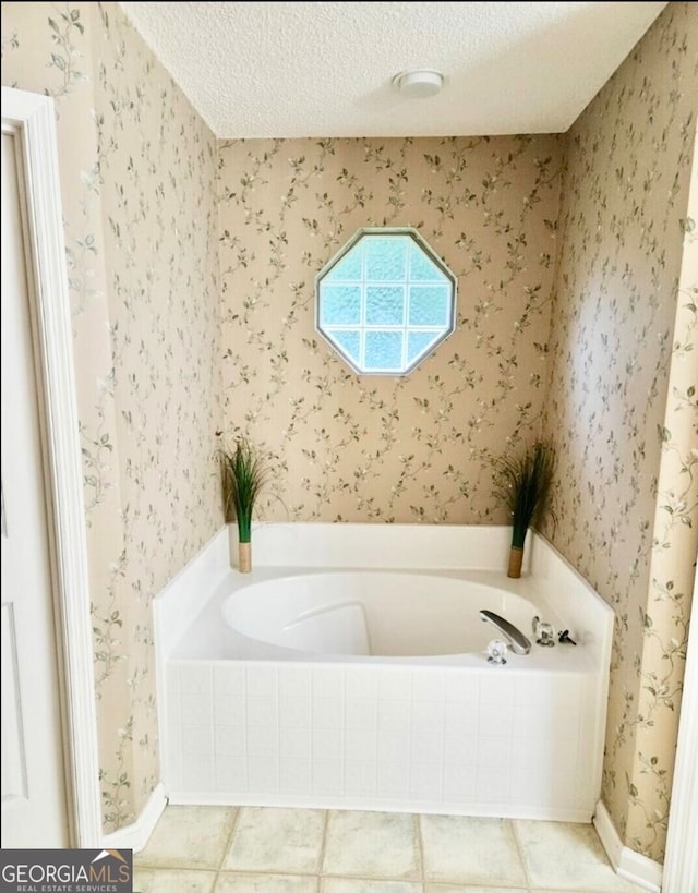 bathroom featuring a textured ceiling, tiled tub, and tile patterned floors