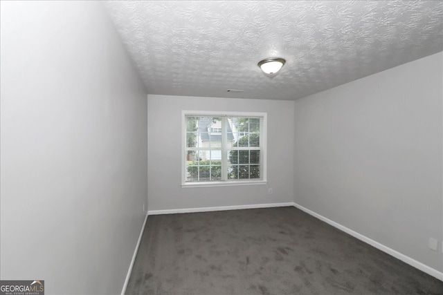 empty room with a textured ceiling and dark carpet