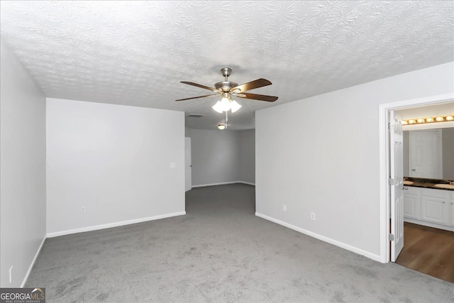 empty room with dark carpet, ceiling fan, and a textured ceiling