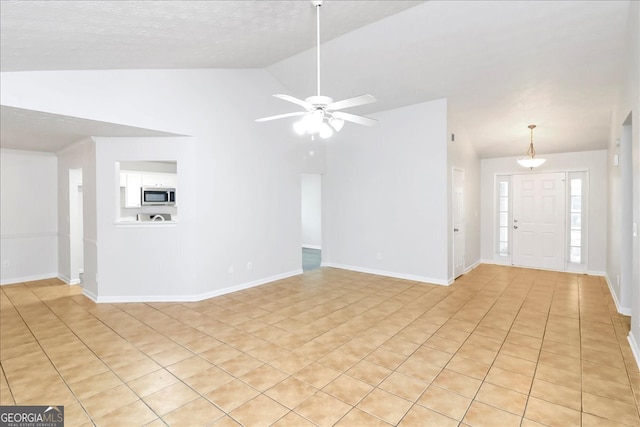 unfurnished living room featuring vaulted ceiling, ceiling fan, and light tile patterned flooring