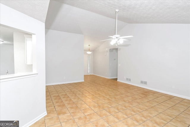 unfurnished room featuring ceiling fan, light tile patterned floors, a textured ceiling, and vaulted ceiling