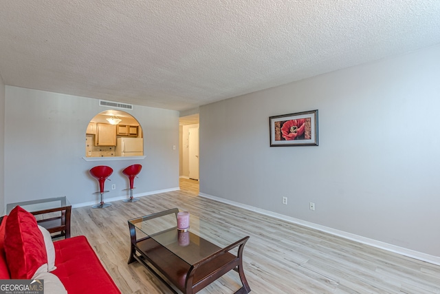 living room featuring light wood-type flooring and a textured ceiling