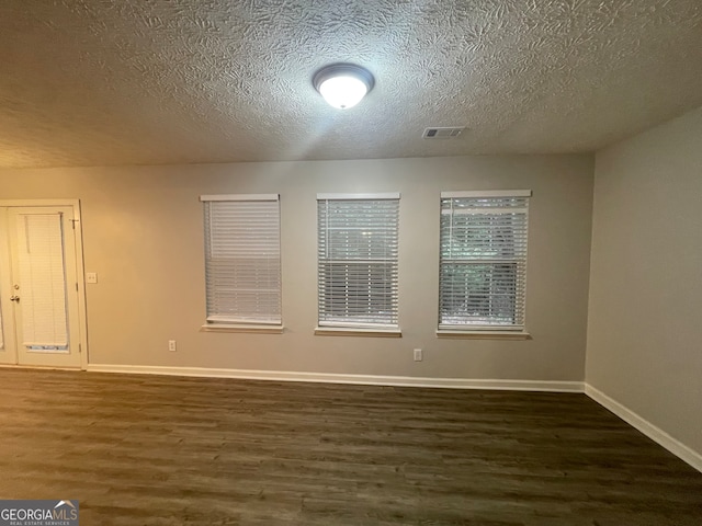 unfurnished room with a textured ceiling and dark hardwood / wood-style flooring