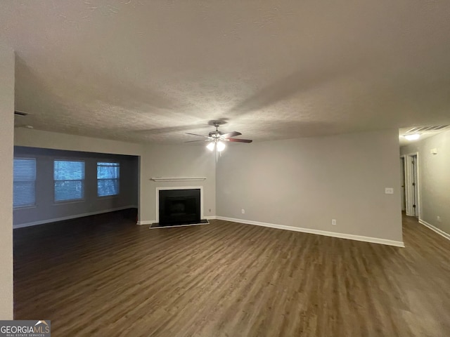 unfurnished living room with ceiling fan, dark hardwood / wood-style floors, and a textured ceiling