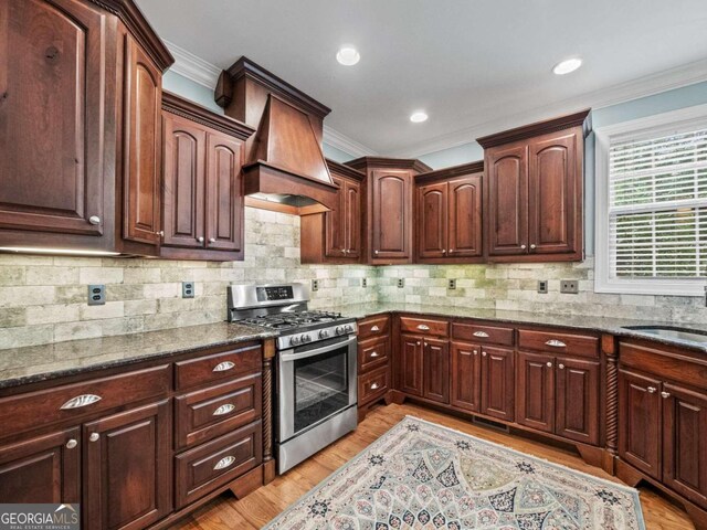 kitchen with light wood-type flooring, stainless steel dishwasher, crown molding, sink, and hanging light fixtures