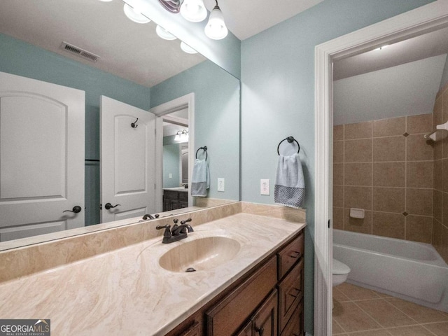 bathroom featuring tile patterned flooring, toilet, and tiled shower / bath