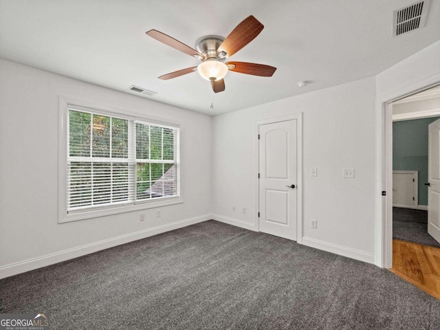 empty room with ceiling fan and dark wood-type flooring