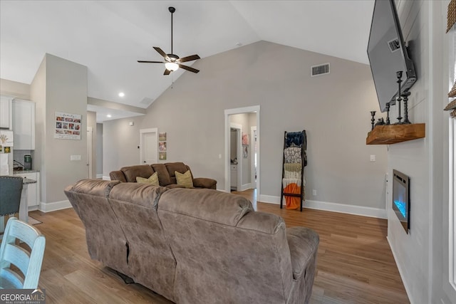 living room featuring light wood-type flooring, ceiling fan, and high vaulted ceiling