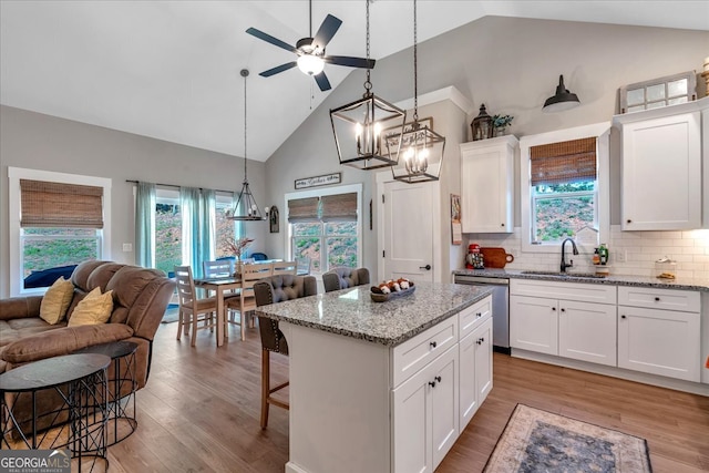 kitchen with white cabinets, sink, a kitchen island, dishwasher, and a breakfast bar area