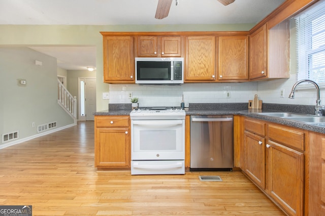 kitchen featuring sink, appliances with stainless steel finishes, light hardwood / wood-style floors, and decorative backsplash