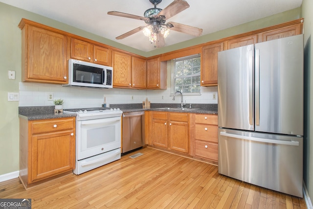 kitchen featuring decorative backsplash, stainless steel appliances, light hardwood / wood-style flooring, ceiling fan, and sink