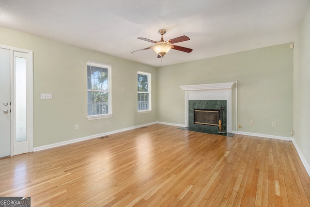 unfurnished living room featuring light hardwood / wood-style flooring, a premium fireplace, and ceiling fan